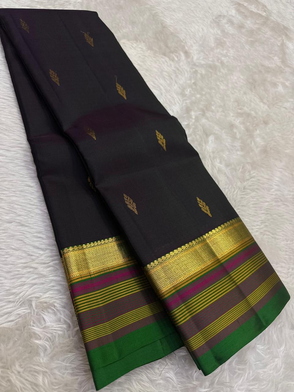 Black pure silk Kanchipuram saree with green pink striped border.