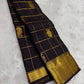 Black kanchipuram silk saree laid lengthwise with gold zari grid checks and gold border detail
