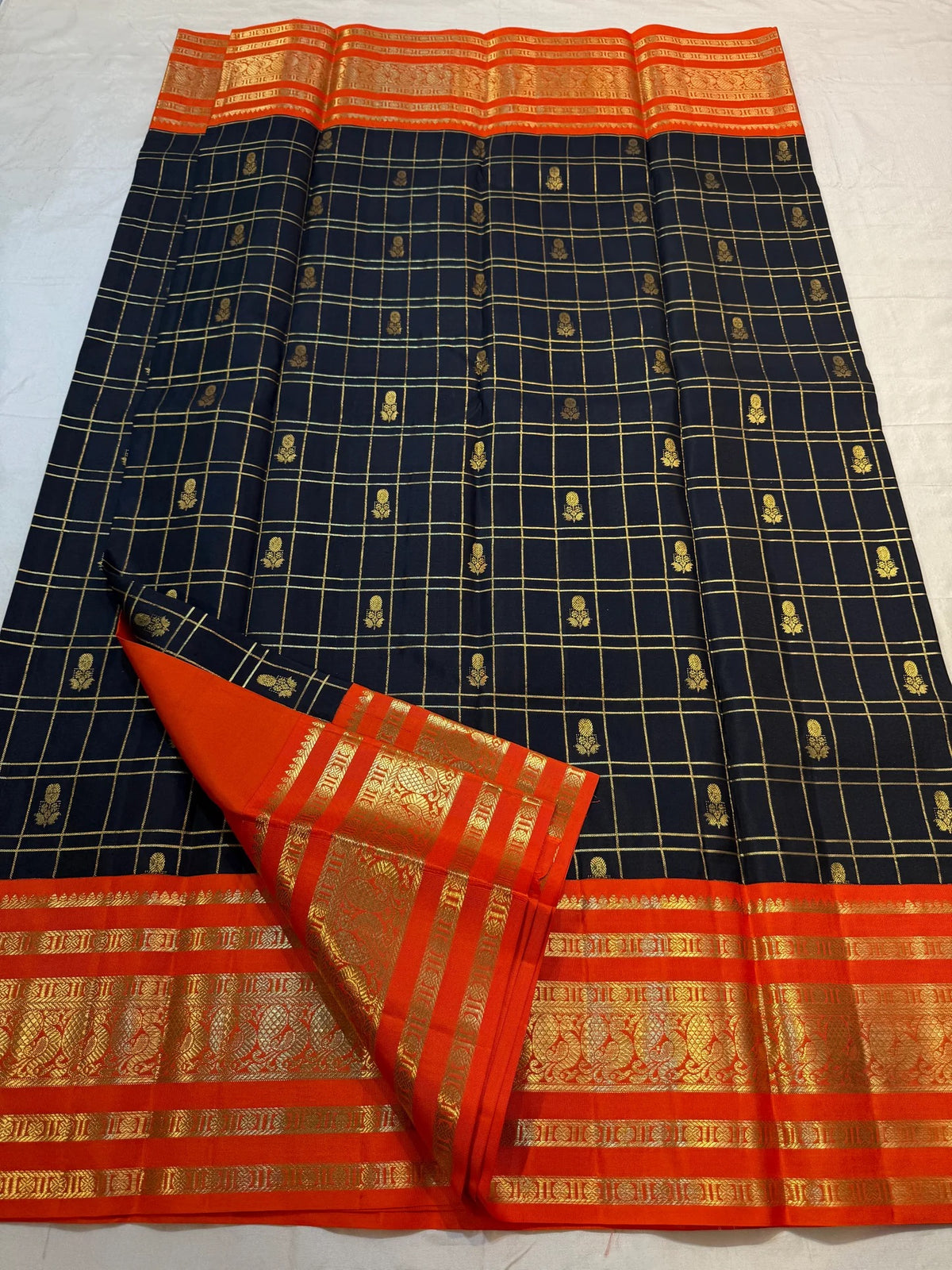 Black, burnt-orange and classic-gold Kanchipuram silk arranged to show checked body, border and rich pallu.