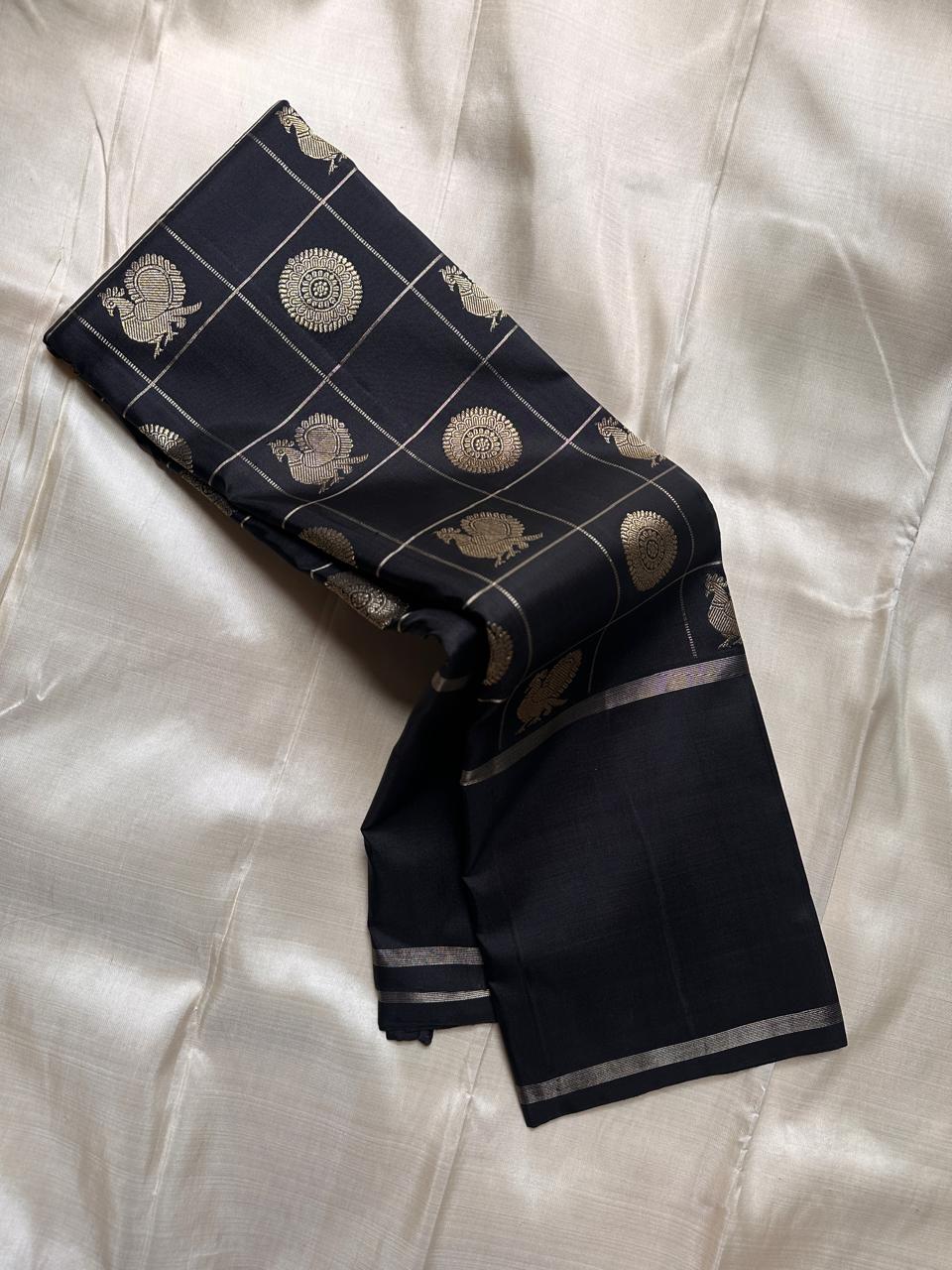 Black Pure Kanchipuram silk saree showing zari woven grid with peacock and circular medallion buttas on the body.