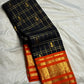 Deep black Kanchipuram silk body with fine classic-gold Zari Kattam grid lines and spaced gold zari buttas.