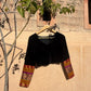 Black velvet blouse on hanger showing full front view with patchwork sleeve panels