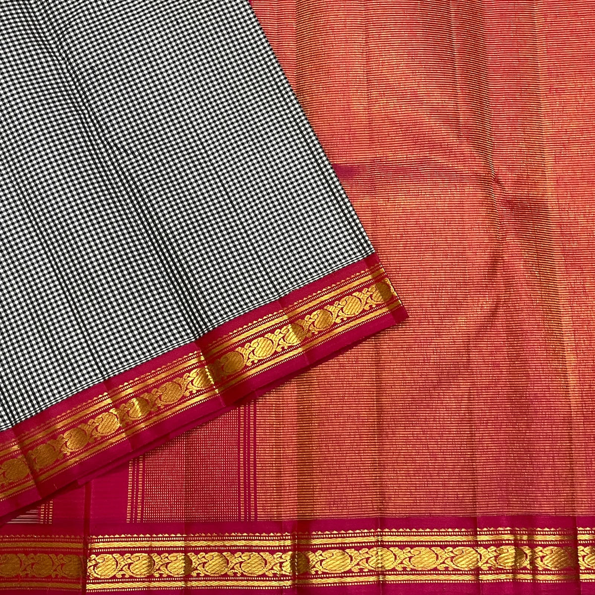 Black and white Kanchi Kattam saree with warm orange-red and pink contrast pallu