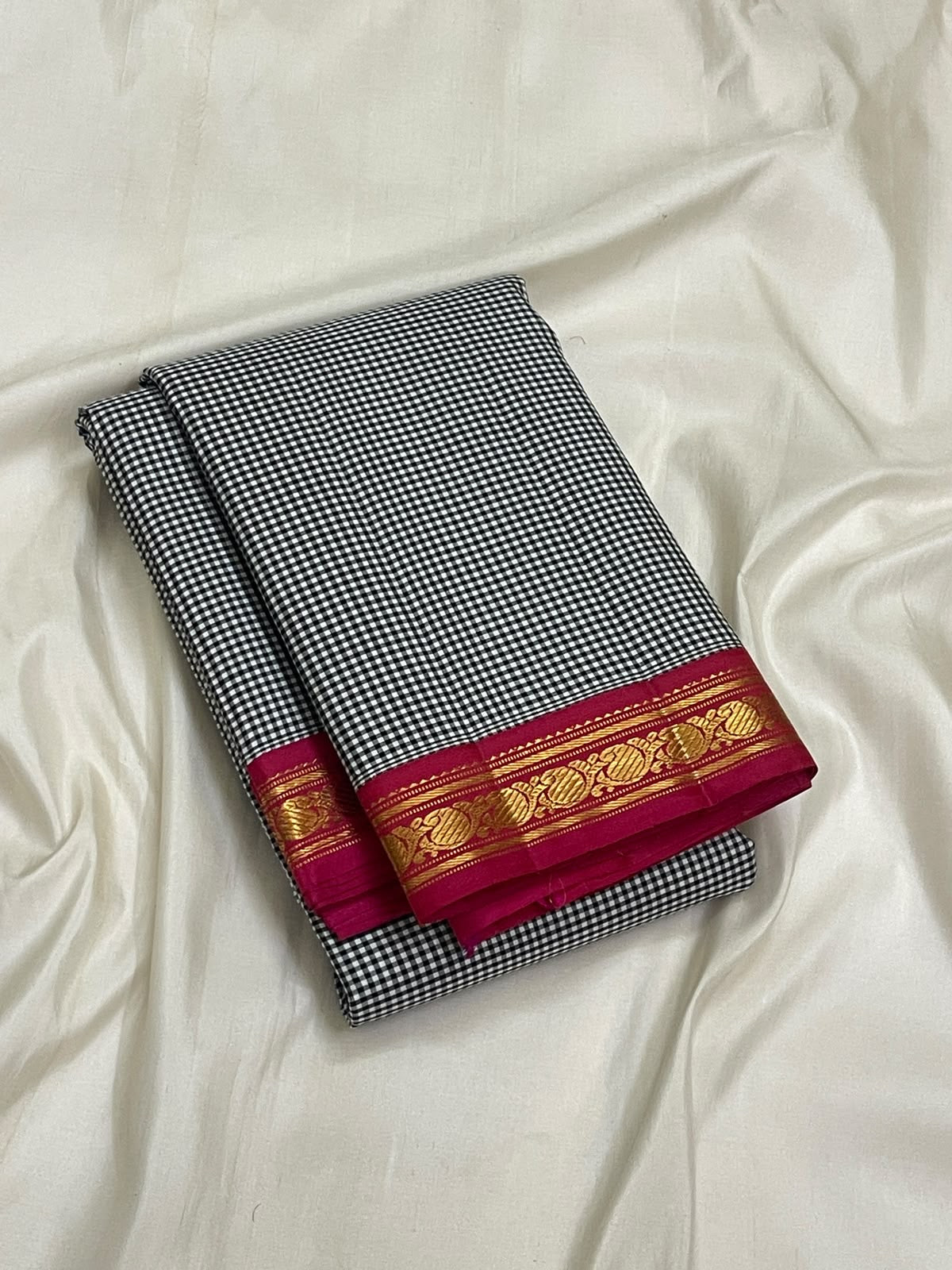 Close view of deep pink Kanchipuram border with repeating gold zari paisley motifs
