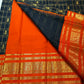 Black Zari Kattam body meeting a saturated burnt-orange border with layered classic-gold zari detailing.