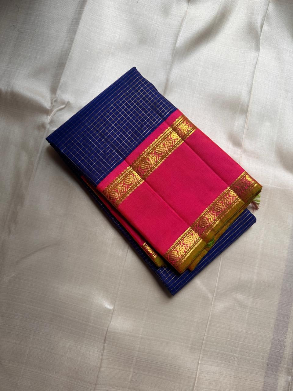 Pure Kanchipuram silk saree folded on ivory background with blue body woven in fine gold checks and bright pink zari border