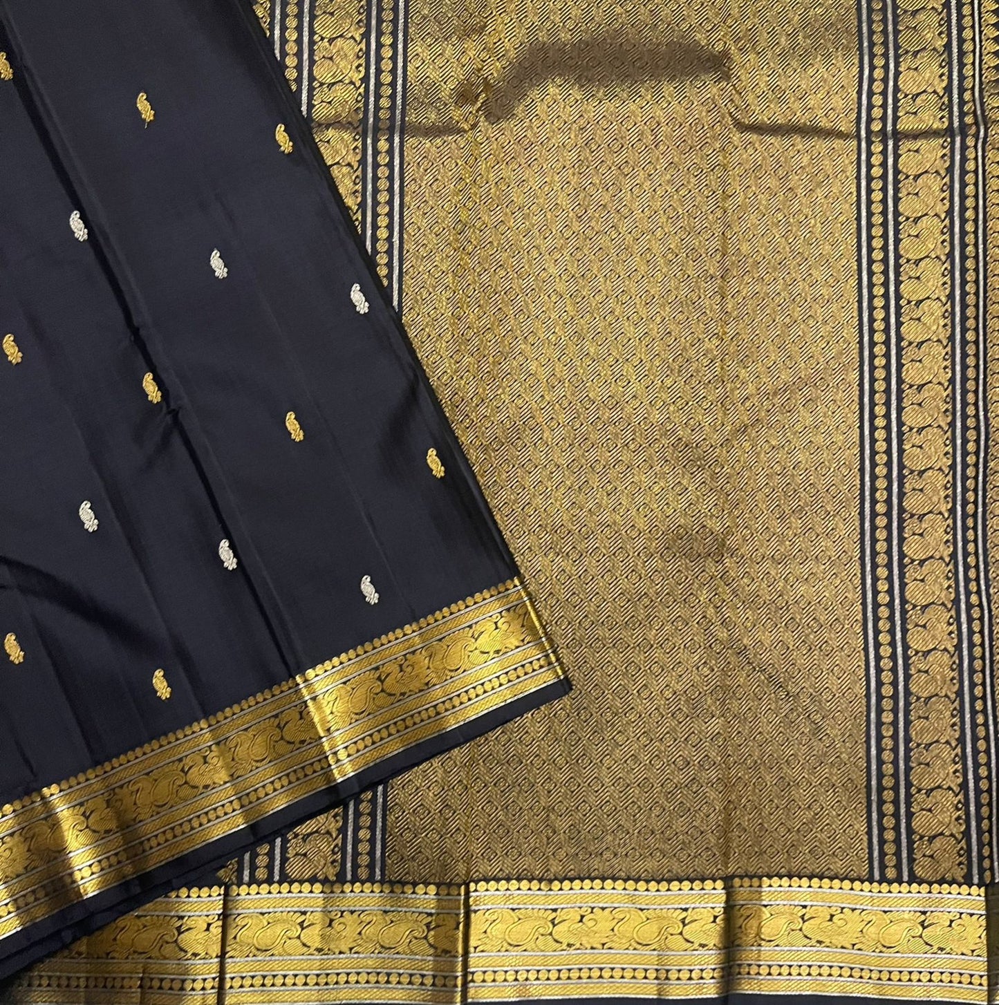 Close-up of the midnight black Kanchipuram silk saree border with intricate paisley detailing and structured antique gold zari bands.