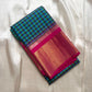 Folded blue-green checked Kanchipuram silk saree with magenta border and gold zari section on an ivory backdrop