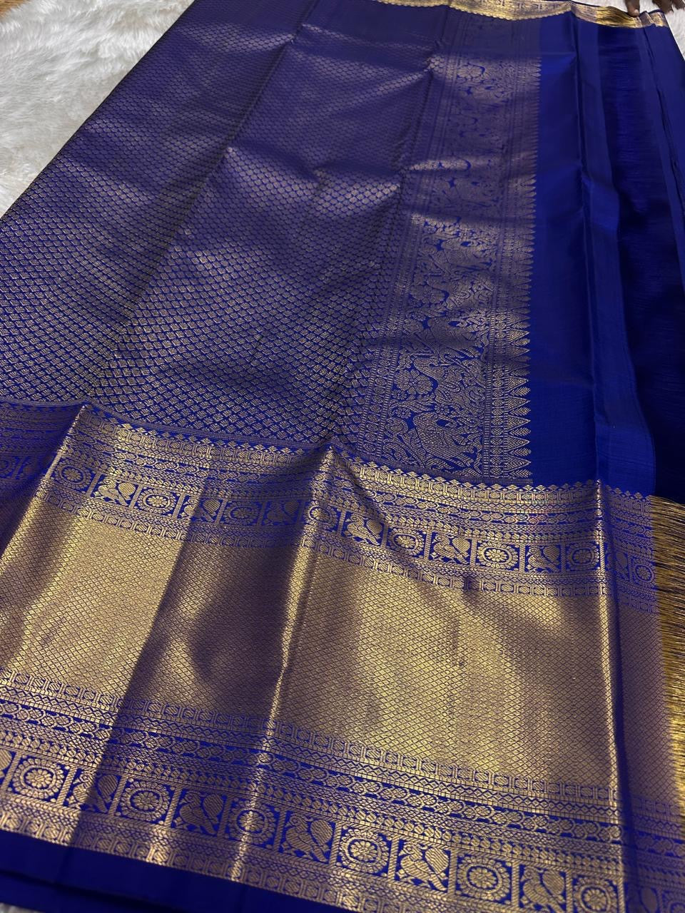 Full spread of royal blue pure Kanchipuram silk saree with gold zari woven pallu and border, flat lay detail
