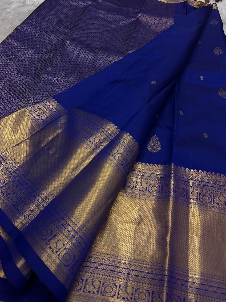 Close view of royal blue saree with gold zari woven body, pallu texture, and wide border detailing