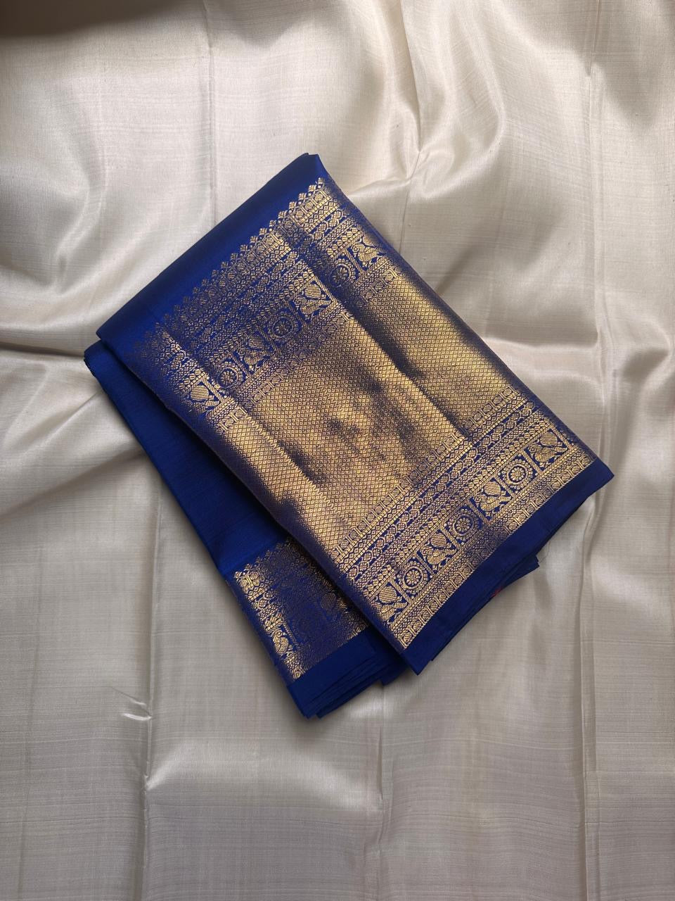 Folded royal blue pure Kanchipuram silk saree with gold zari woven border, flat lay, shipped from New Jersey USA