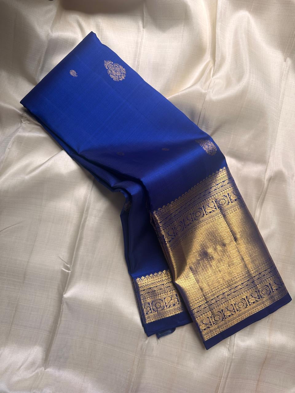 Royal blue pure Kanchipuram silk saree folded to show gold zari border and pallu panel on a light background
