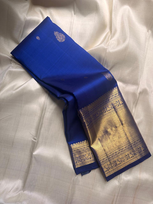 Royal blue pure Kanchipuram silk saree folded to show gold zari border and pallu panel on a light background