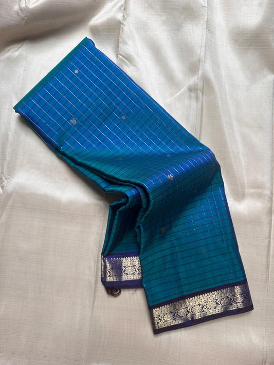 Blue muthu kattam Pure Kanchipuram Silk Saree shown draped with indigo zari woven border and silver motifs on the body