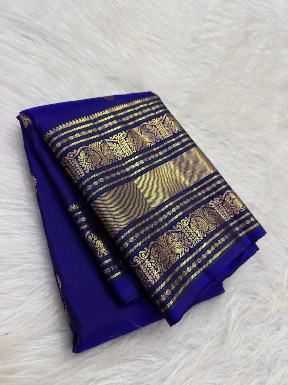 Royal blue Kanchipuram saree with an ornate peacock-arch zari border.