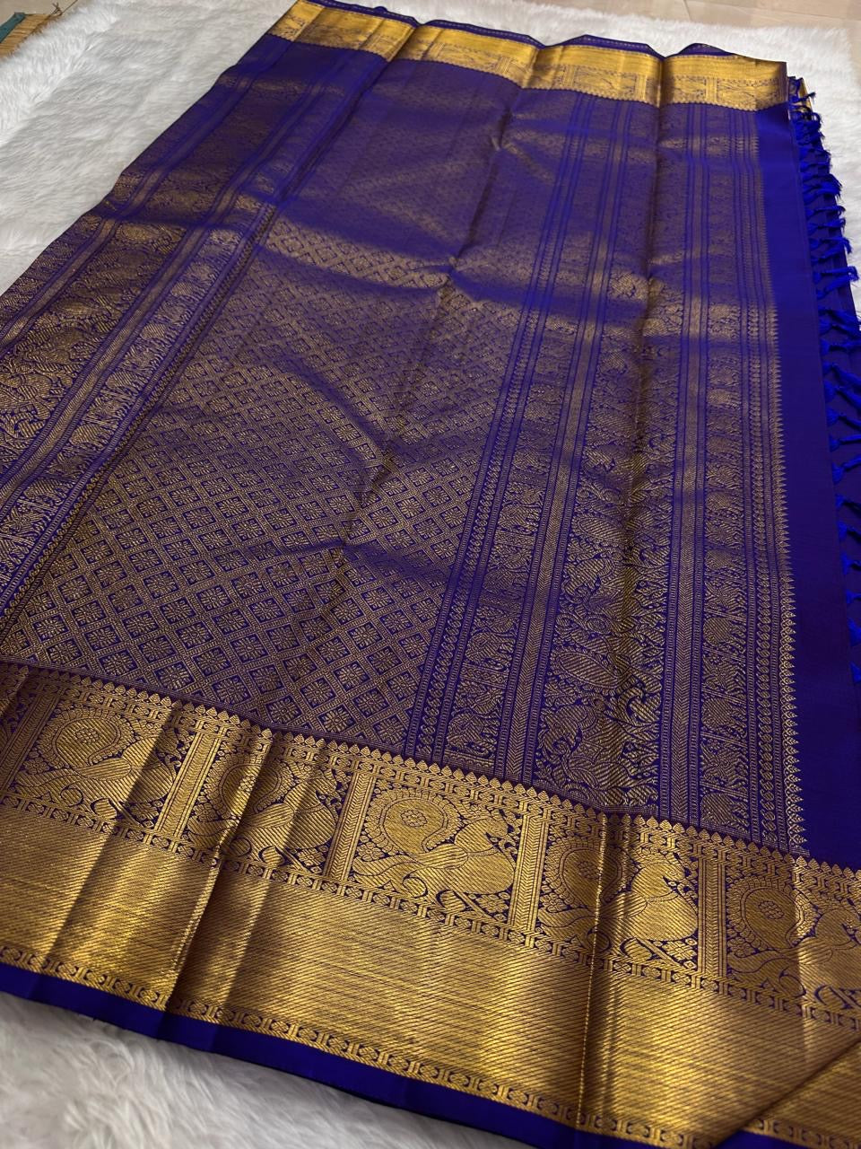 Broad gold zari border with large detailed handwoven peacock motifs on royal blue Kanchipuram silk.