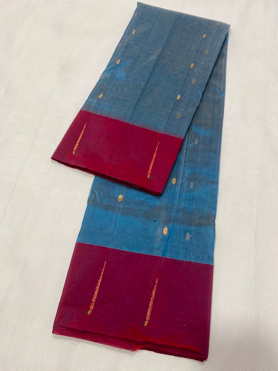 Folded Teal Blue and Raspberry Pink Tissue Silk Chanderi saree with minimal metallic woven details.