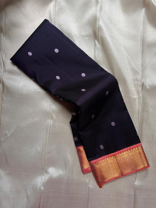 Inky blue Kanchipuram silk saree folded to show peach zari border with antique gold geometric weave and evenly spaced round buttas on the body