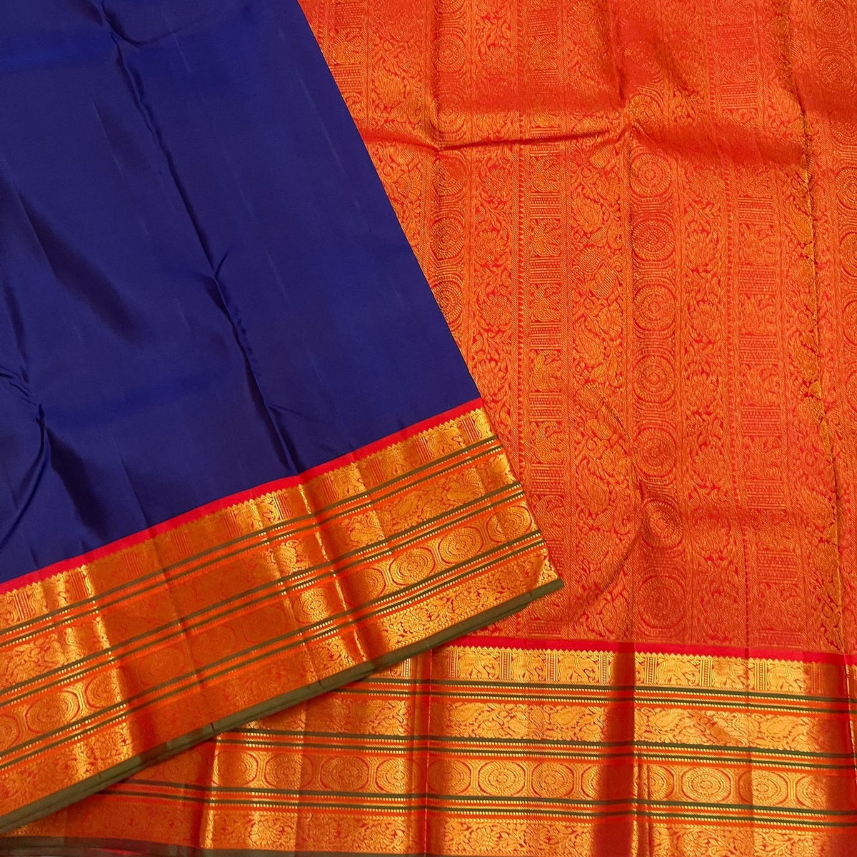 Royal-blue silk meeting a burnt-orange Varisaipet border with broad classic-gold zari registers.