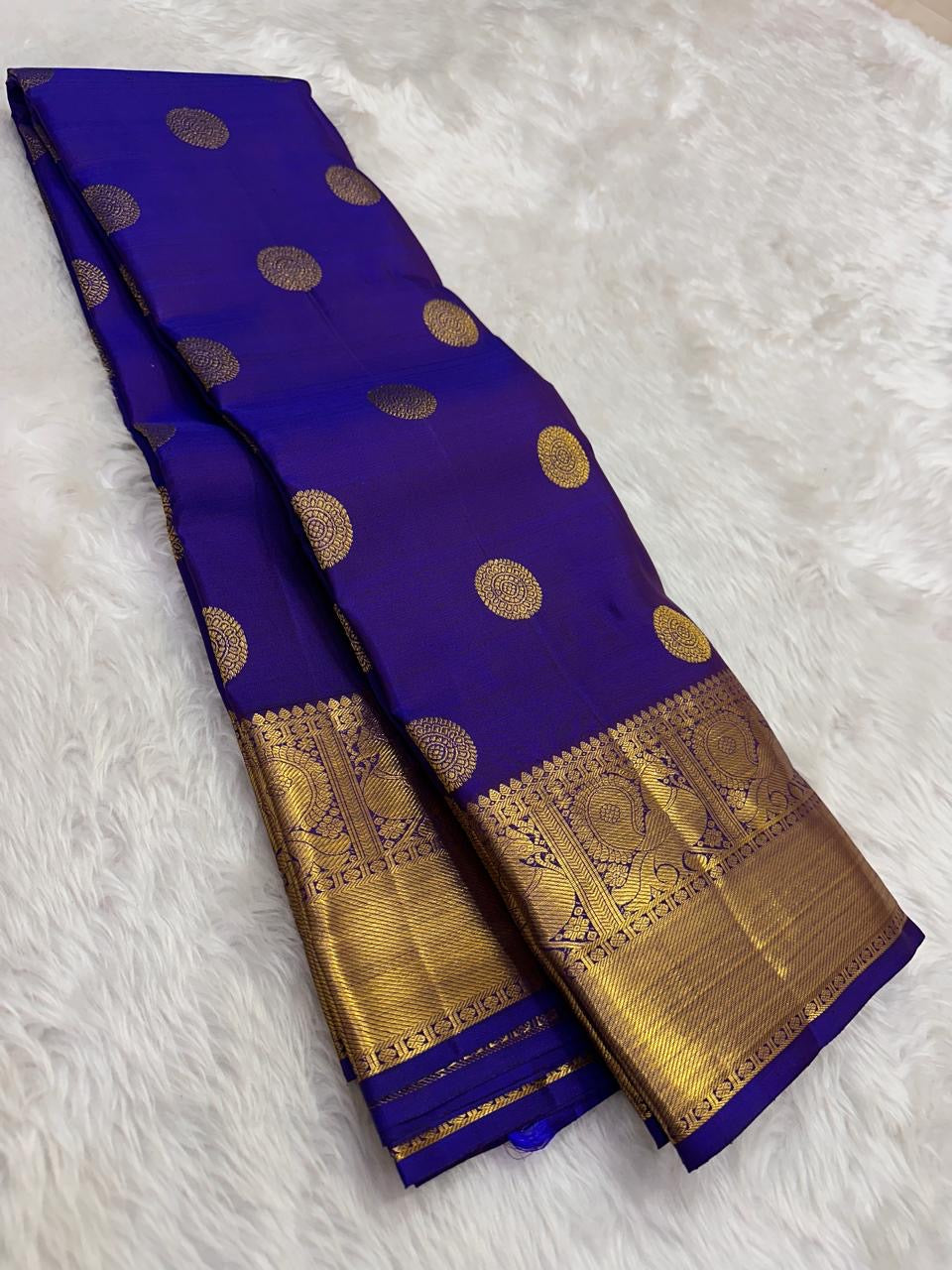 Royal blue silk body with circular multi-layer Kamalam zari buttas arranged across the saree.