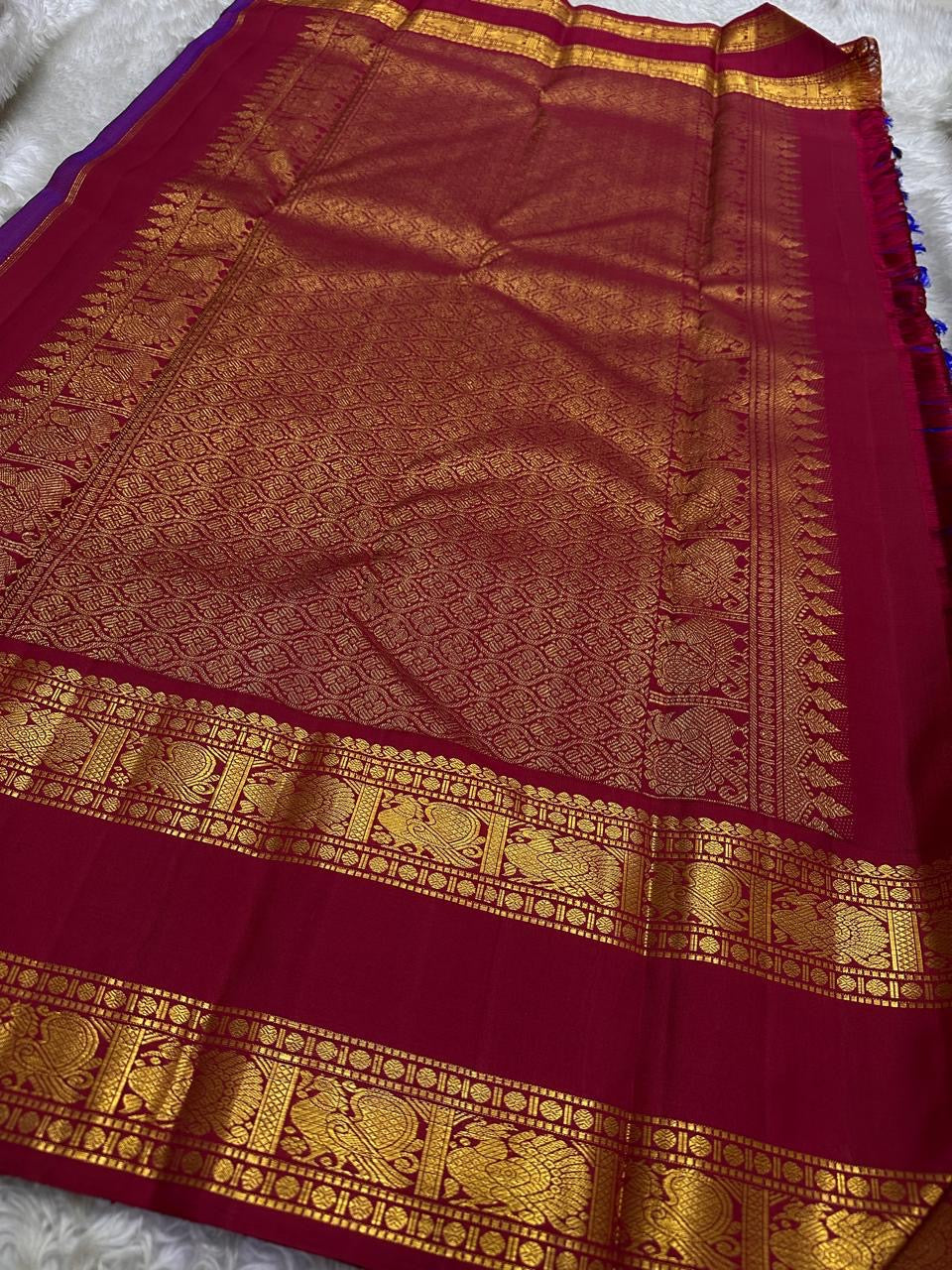 Wide maroon pallu spread with intricate gold zari woven work and border panels, available in the USA.