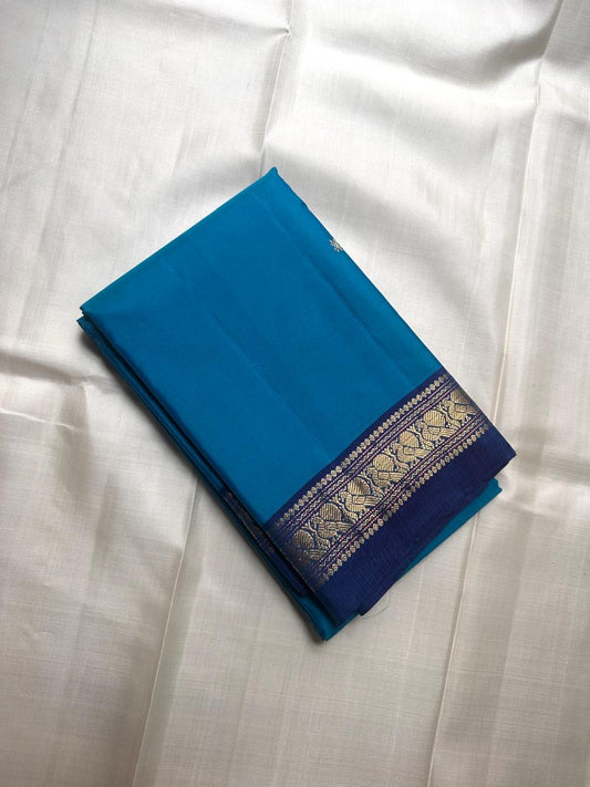 Folded pure Kanchipuram silk saree in blue with narrow zari peacock border visible along the edge