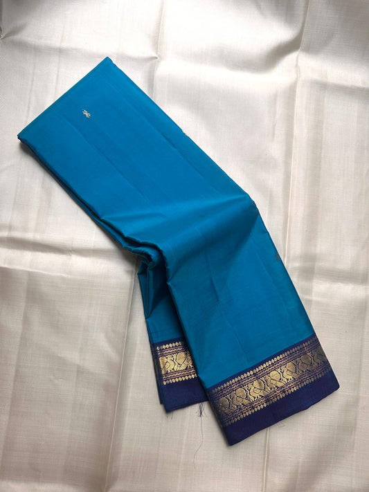 Pure Kanchipuram silk saree laid open showing blue body with small scattered zari buttas and contrast zari border available in the USA