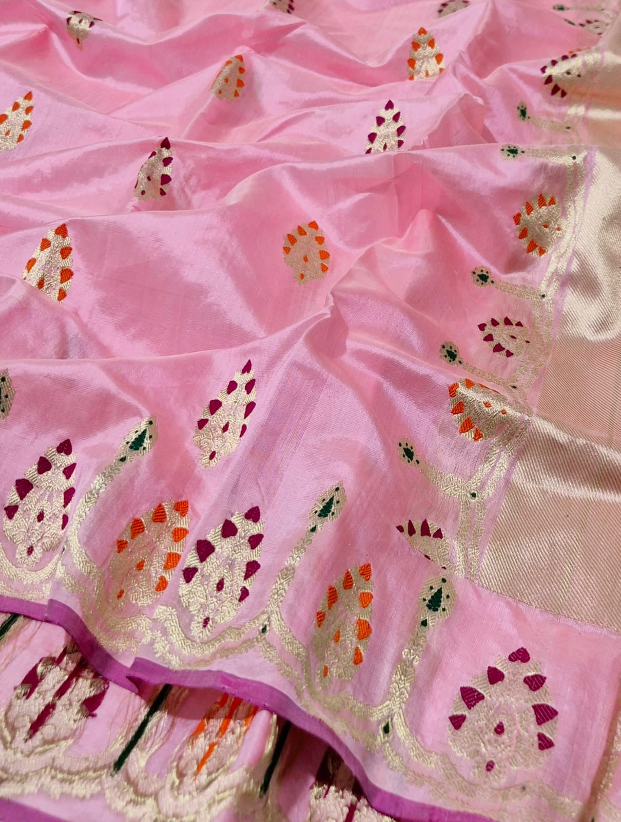 Close view of blush pink Pattu Silk Chanderi saree with gold motifs accented in magenta orange and green