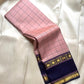 Draped blush pink checked pure Kanchipuram silk saree showing deep navy zari border with star motifs on a white fabric background