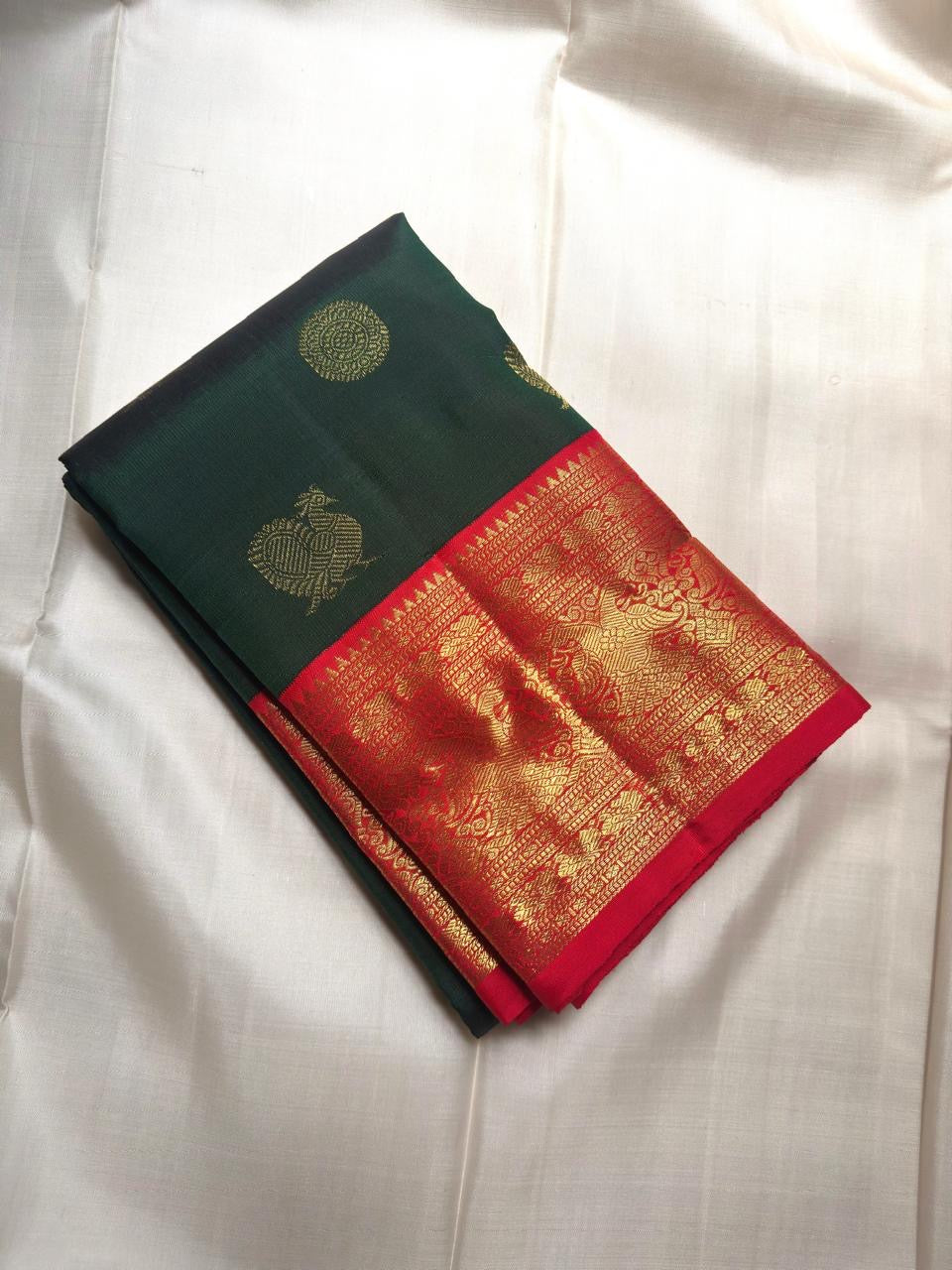 Kanjivaram butta saree in bottle green with Mayil Chakram buttas across the body