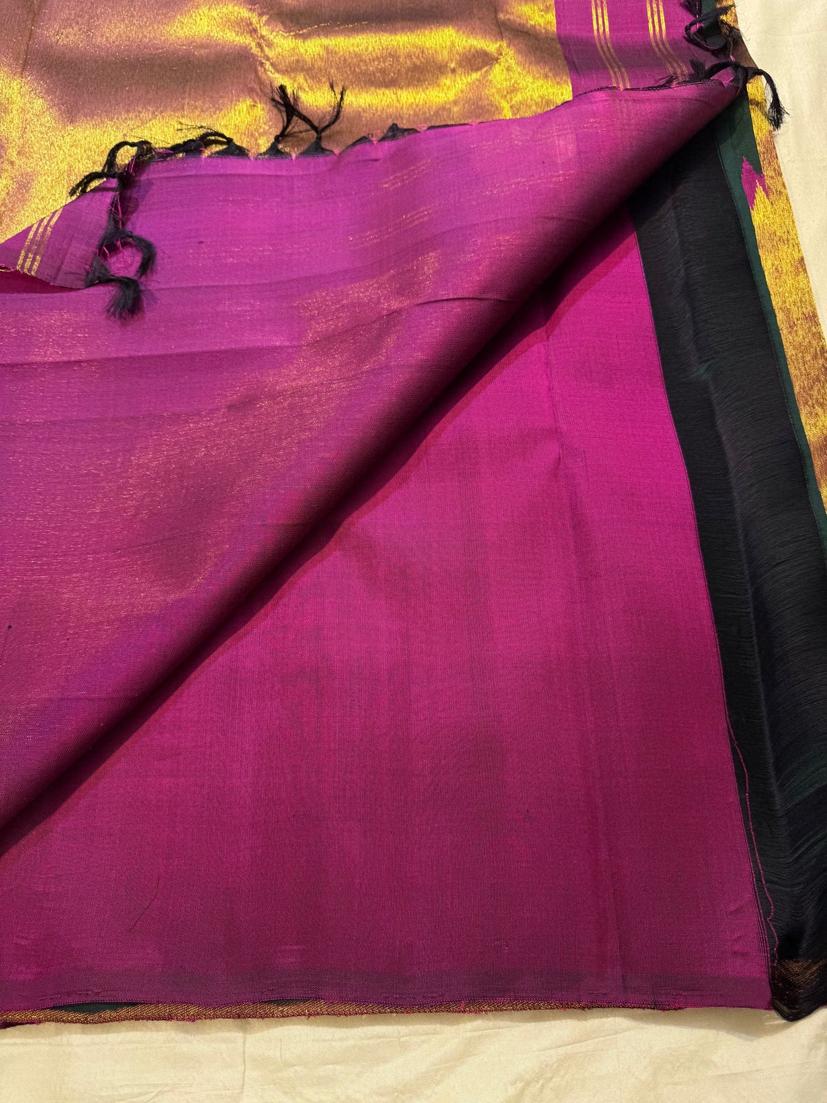 Detail of the copper-gold border and Vadamalli magenta geometry on the bottle green Kanjeevaram saree
