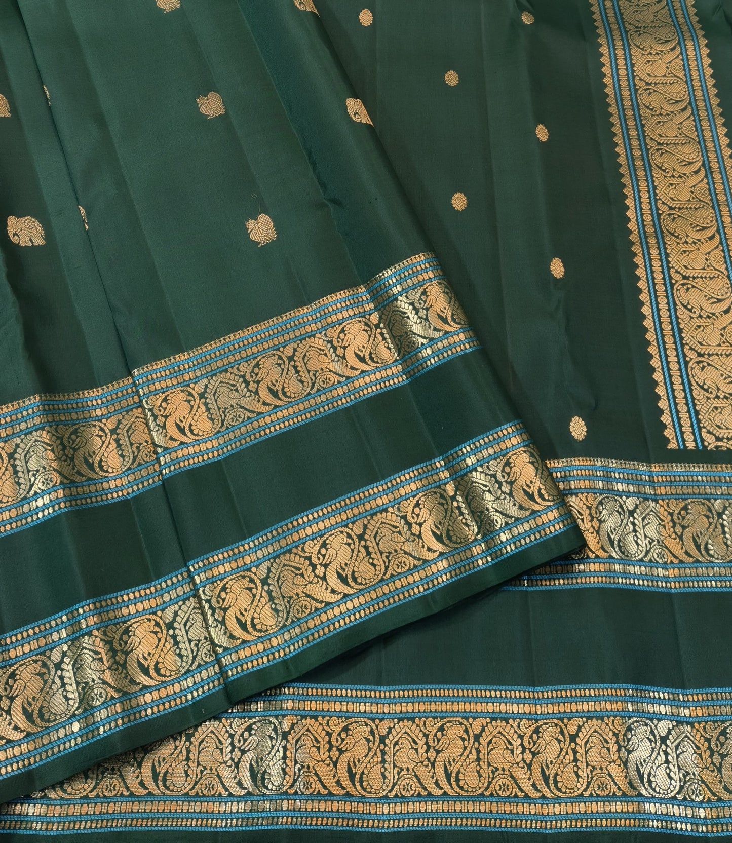 Close view of antique-gold zari buttas woven across the bottle-green pure silk body.