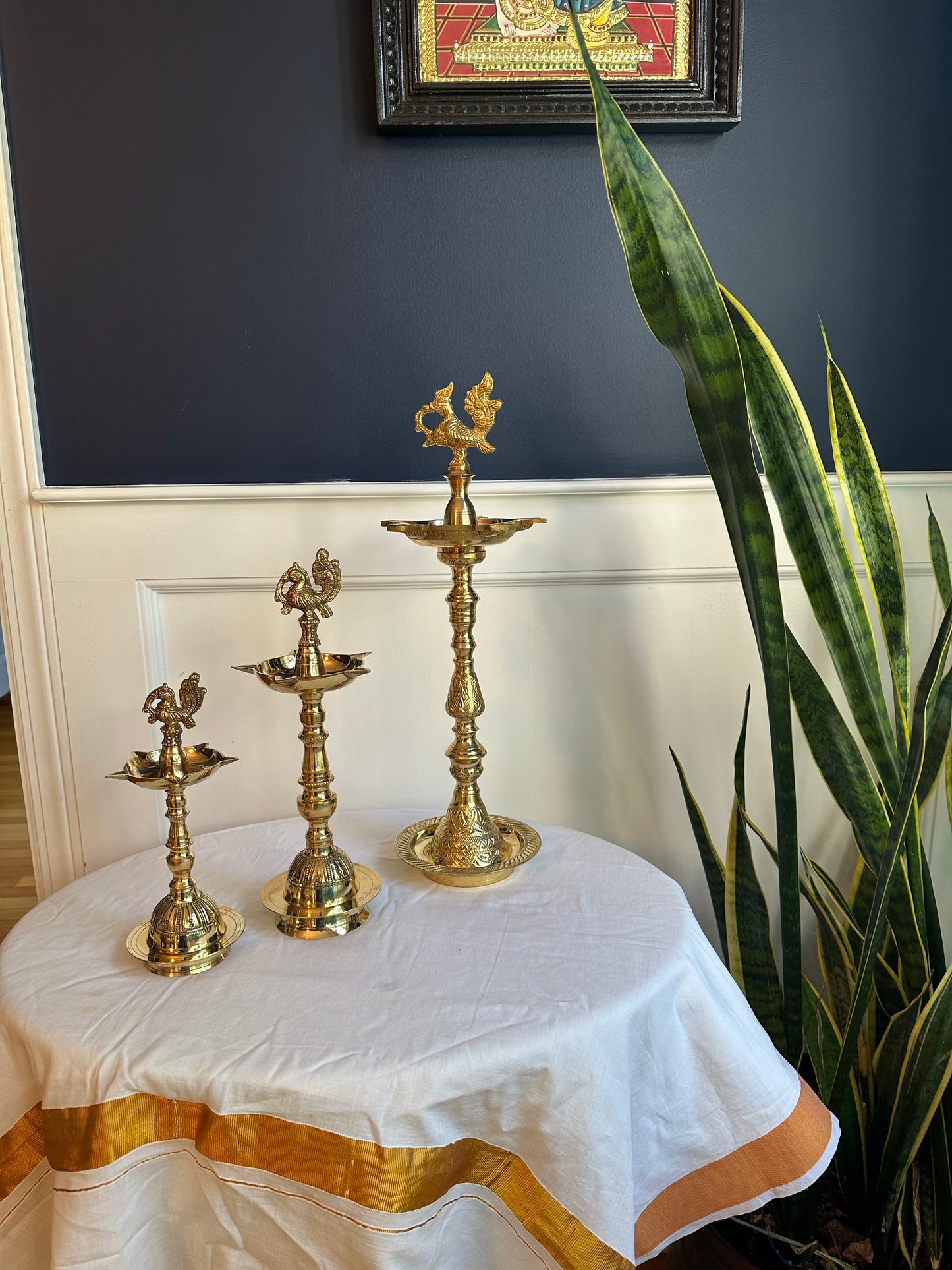 Close-up of solid brass Kuthu Vilakku lamp with detailed peacock and naga top design
