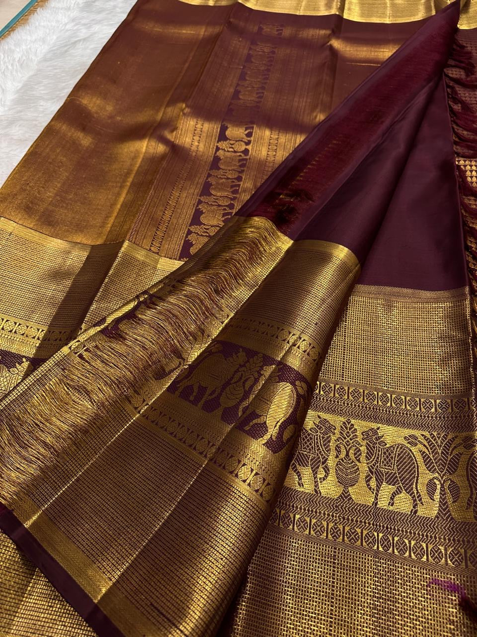 Close view of broad antique-gold elephant border on Deep Maroon Brown Kanjivaram silk.