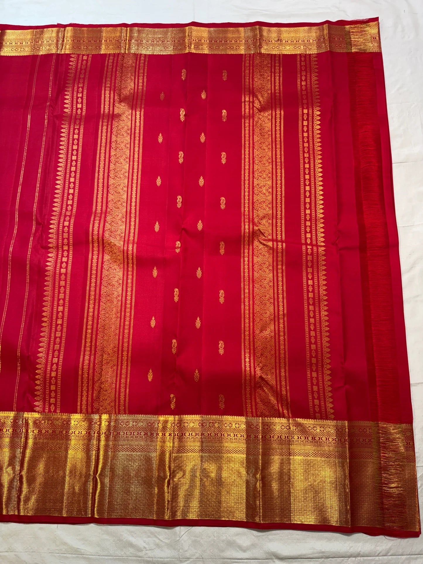 Close border view showing dense gold geometric weaving along the red silk edge.