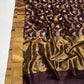 Folded Deep Cocoa Brown Pattu Silk Chanderi showing contrasting gold floral vines and silver-tone bird motifs.