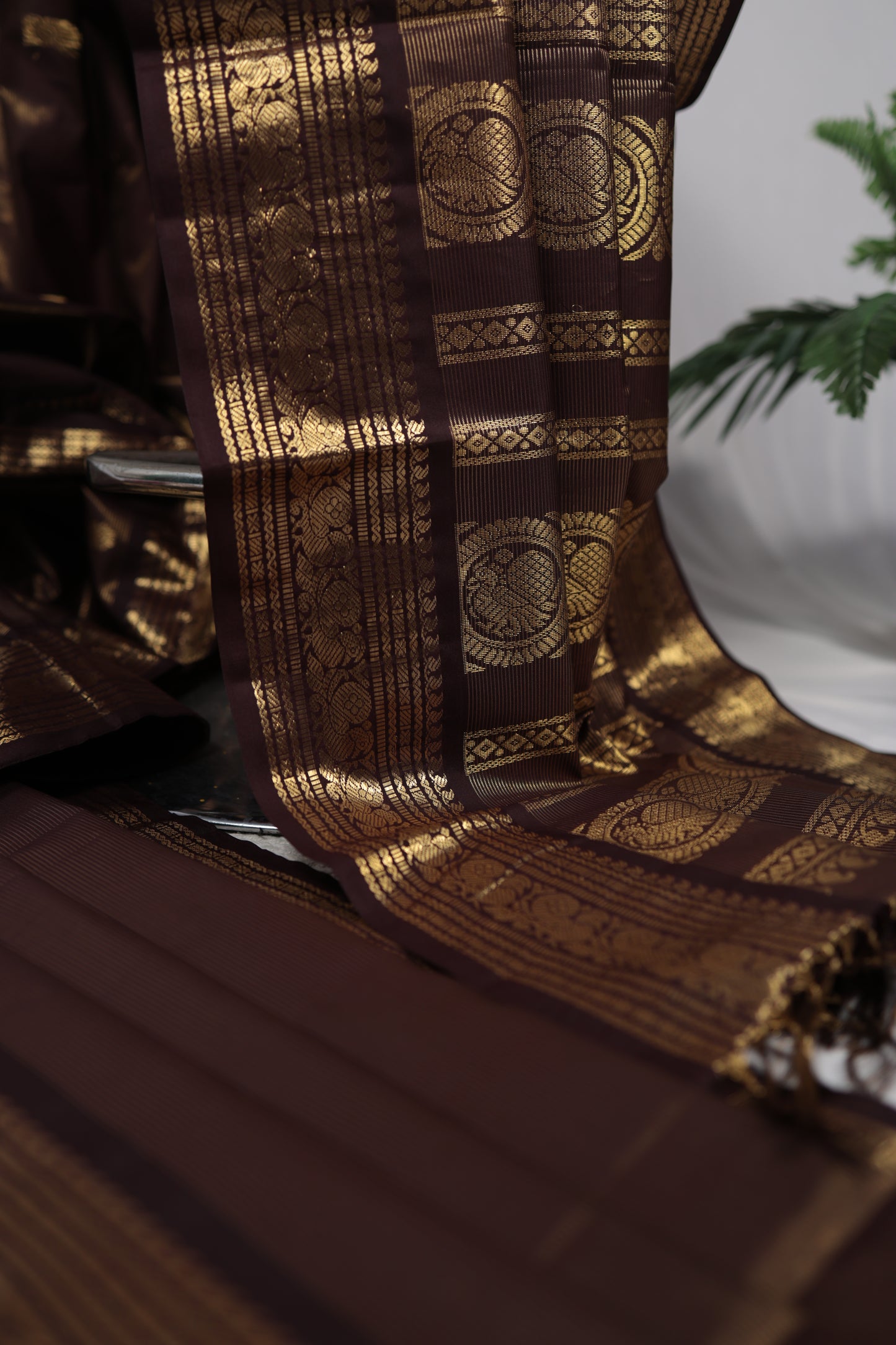 Folded deep brown vairaoosi Kanchipuram silk saree with zari woven border on white fabric, available in the USA
