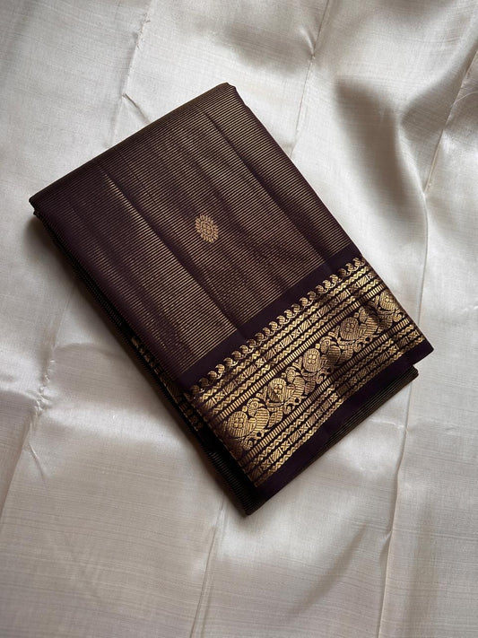 Full drape deep brown vairaoosi Kanchipuram silk saree with zari woven border over red chair