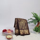 Brown saree with gold patterns on a white surface with decorative elements.