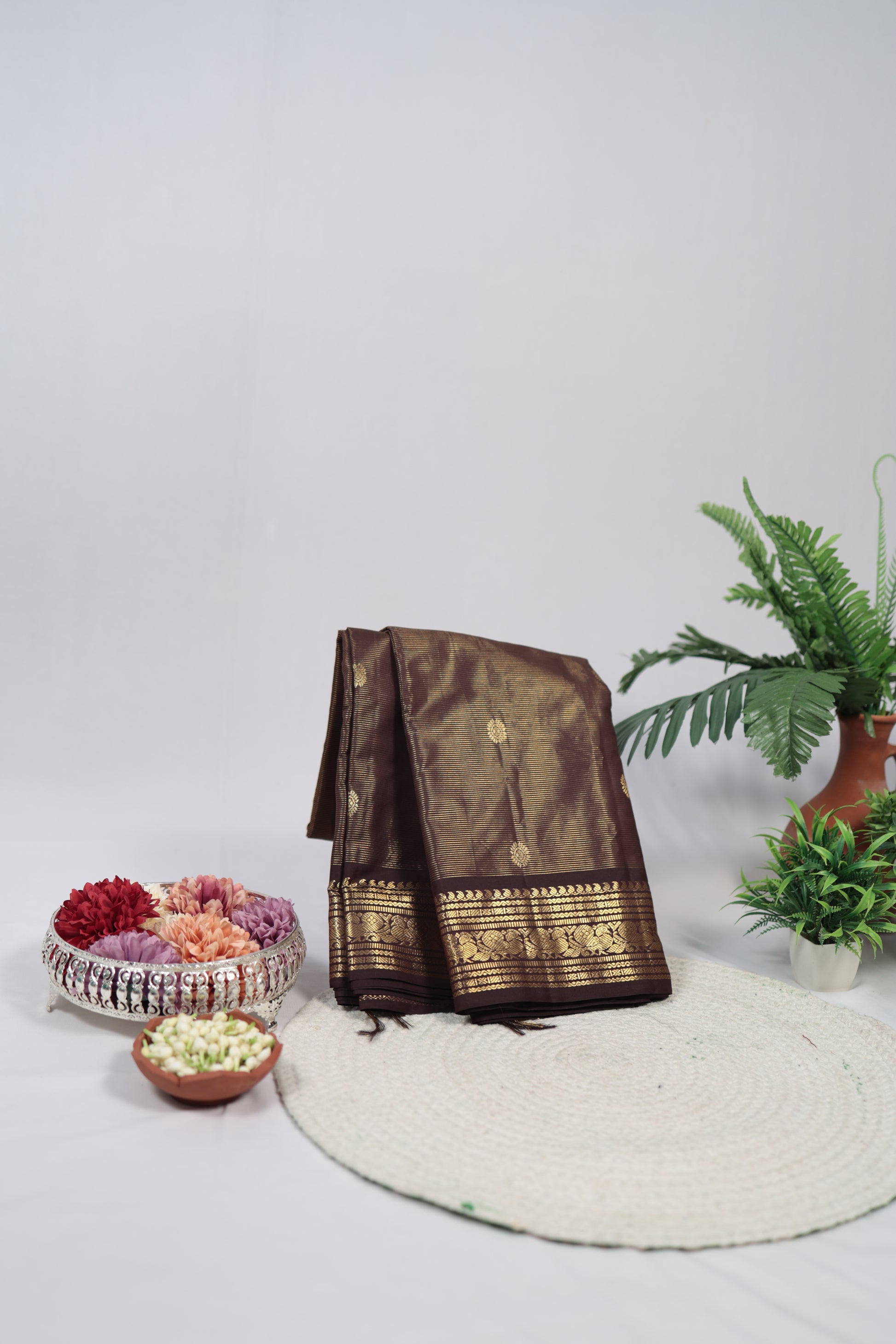 Brown saree with gold patterns on a white surface with decorative elements.