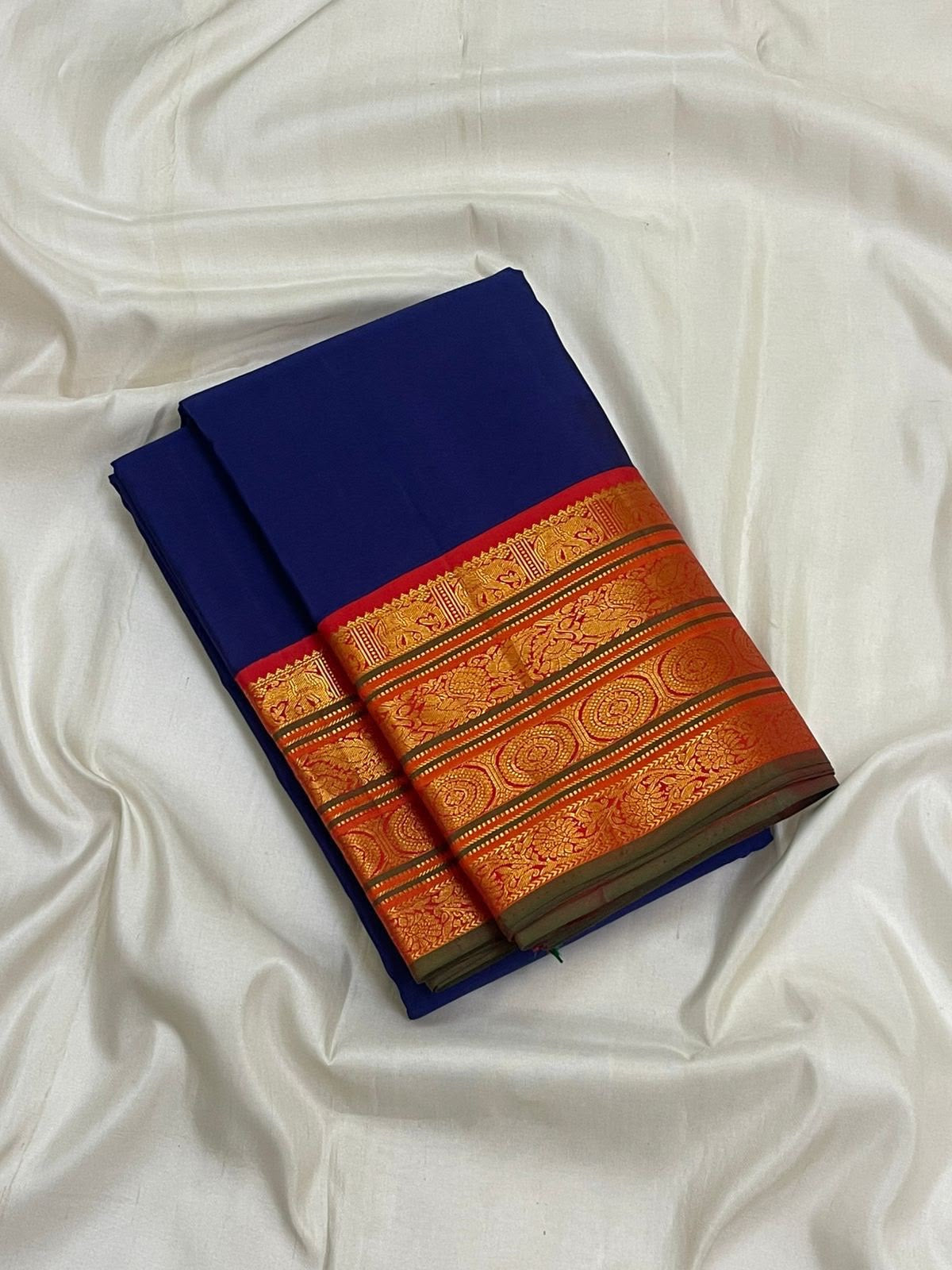 Burnt-orange Kanchipuram border with circular medallion-like gold-zari forms and fine ornamental bands.