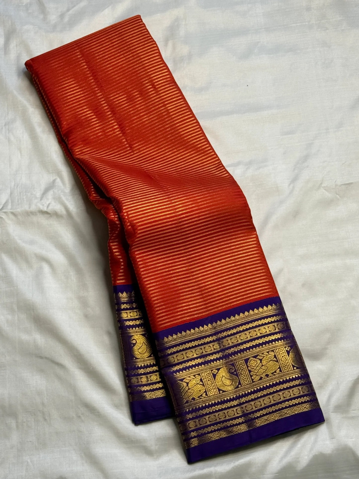 Close view of antique-gold zari lines woven on Burnt Orange Kanjivaram silk.