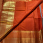 Burnt-orange Pure Silk Kanchipuram saree draped, showing the warm brown undertone
