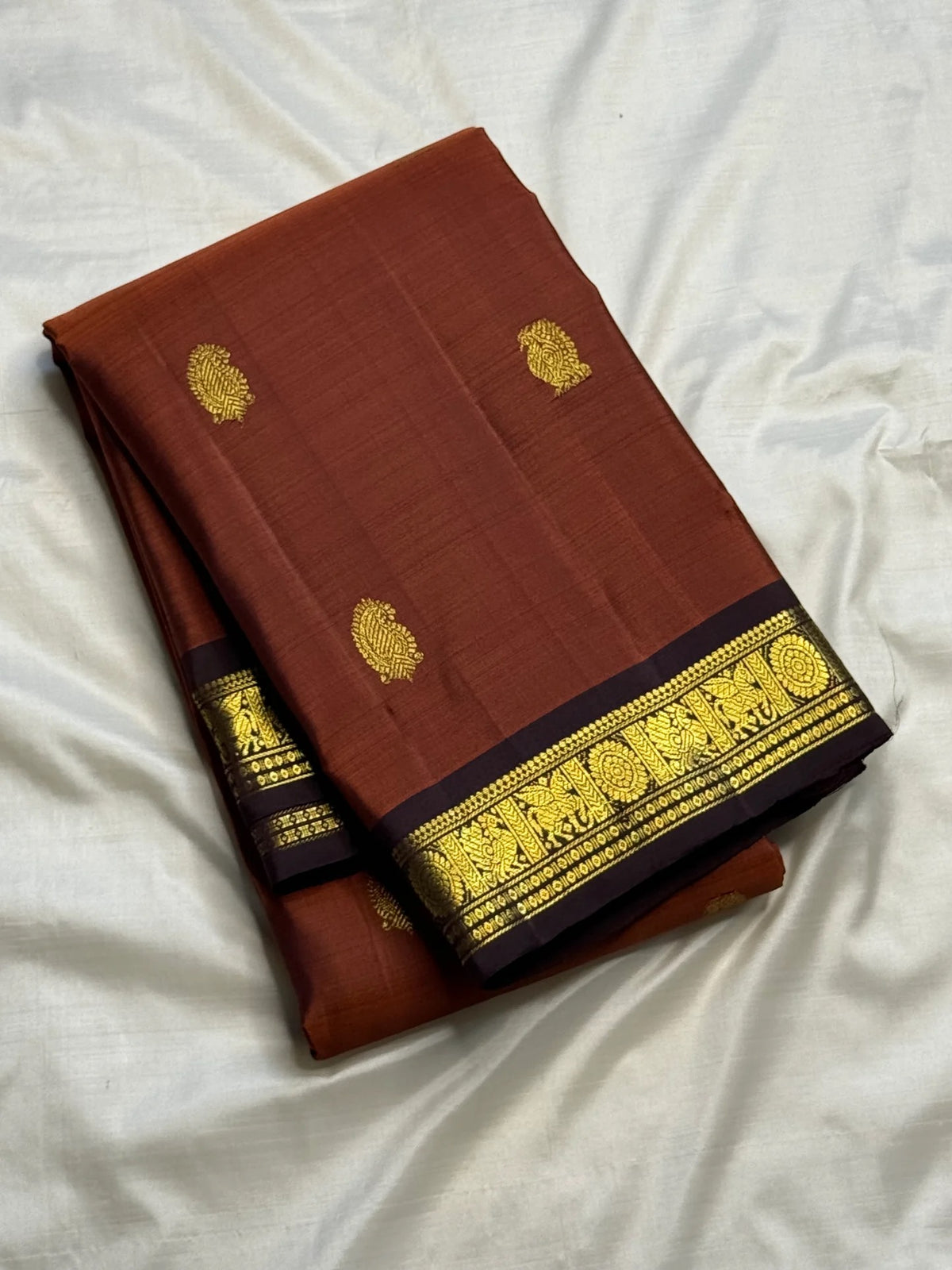 Close view of antique-gold zari buttas woven on Burnt Rust Kanjivaram silk.