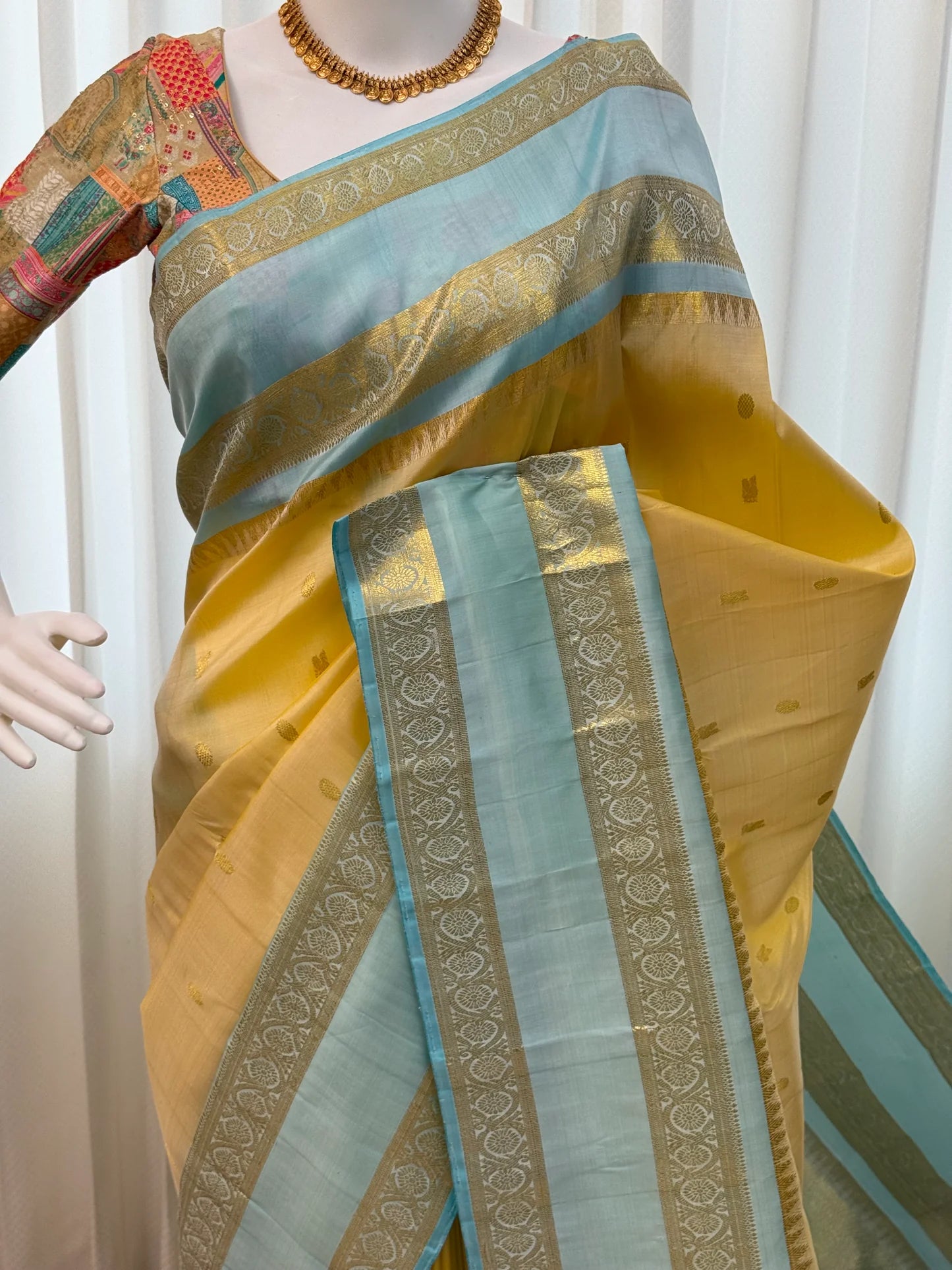 Mannequin drape of butter yellow Pure Kanchipuram silk saree with sky blue border and zari woven panels, shipped from New Jersey USA