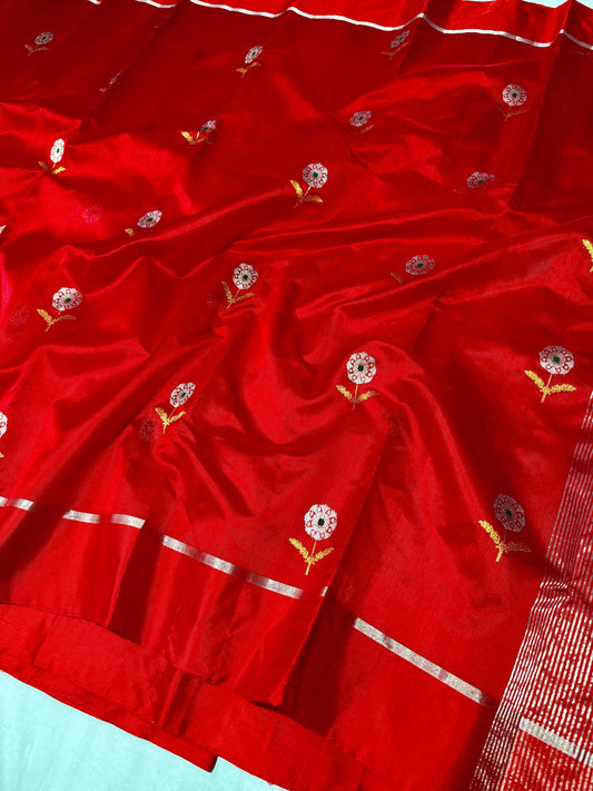 Close view of the vermilion red Chanderi saree's small floral butas and metallic-toned border stripes