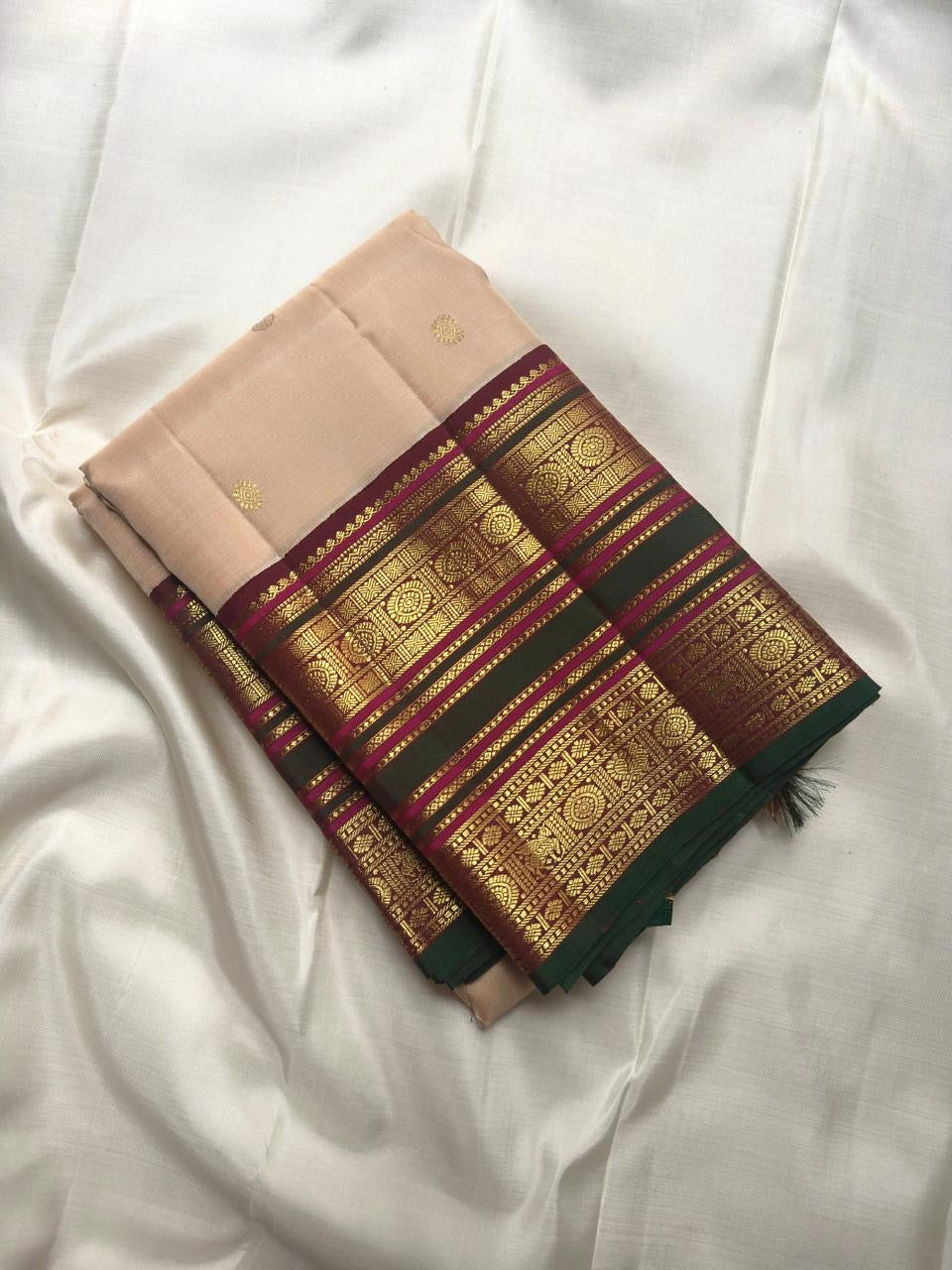 Soft peach ivory Kanchi Pattu silk saree with gold buttas and maroon forest green border.