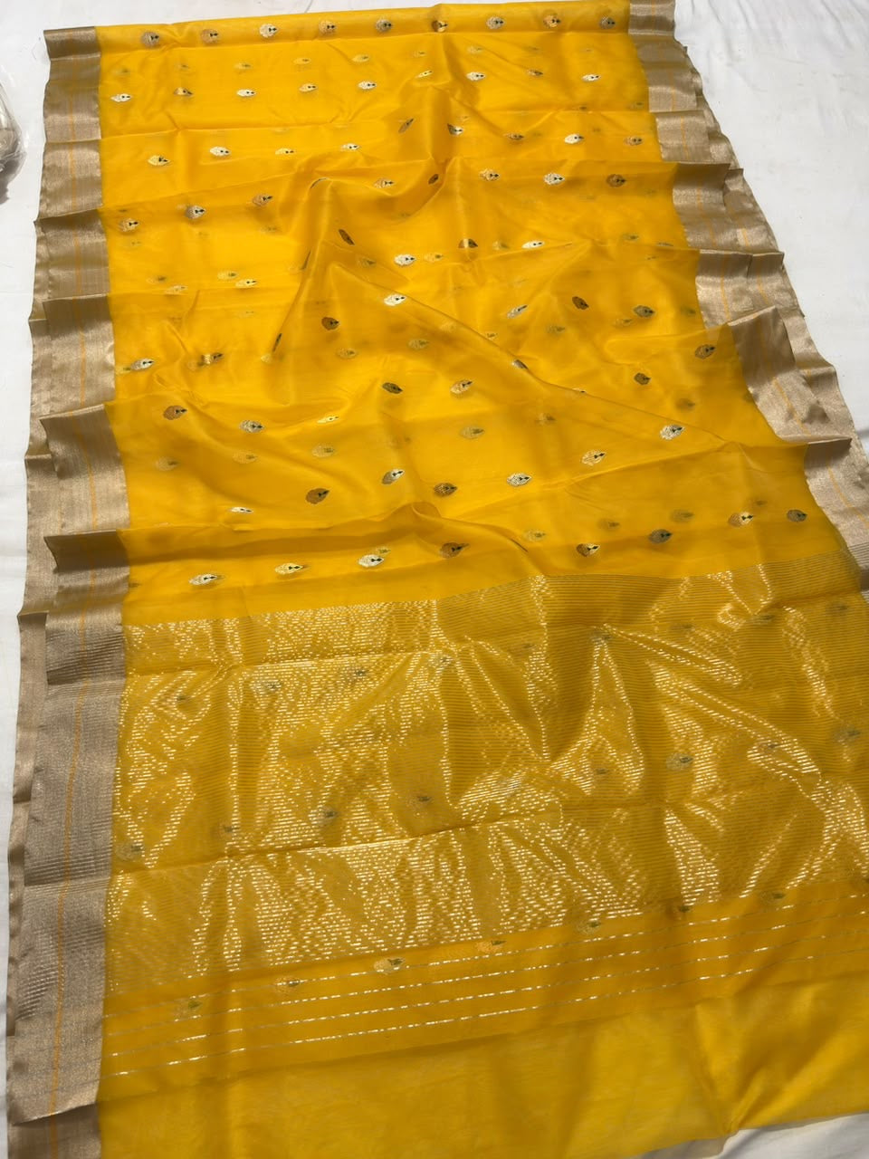 Turmeric yellow Chanderi saree opened to show the champagne-silver borders and luminous woven pallu