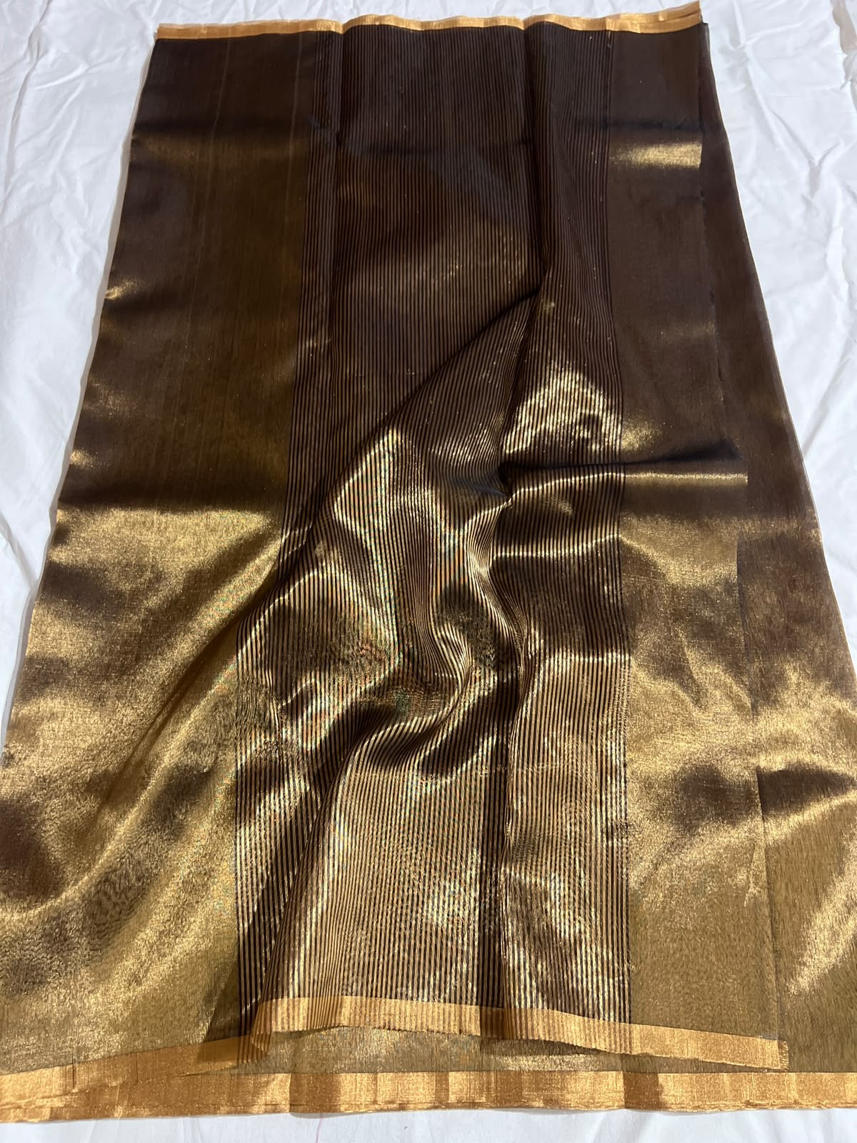 Folded bronze and antique-gold Chanderi handloom silk showing luminous texture and warm gold-toned border detail.