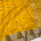 Turmeric golden yellow Katan silk Chanderi saree laid open showing small pale buttas and champagne-silver border